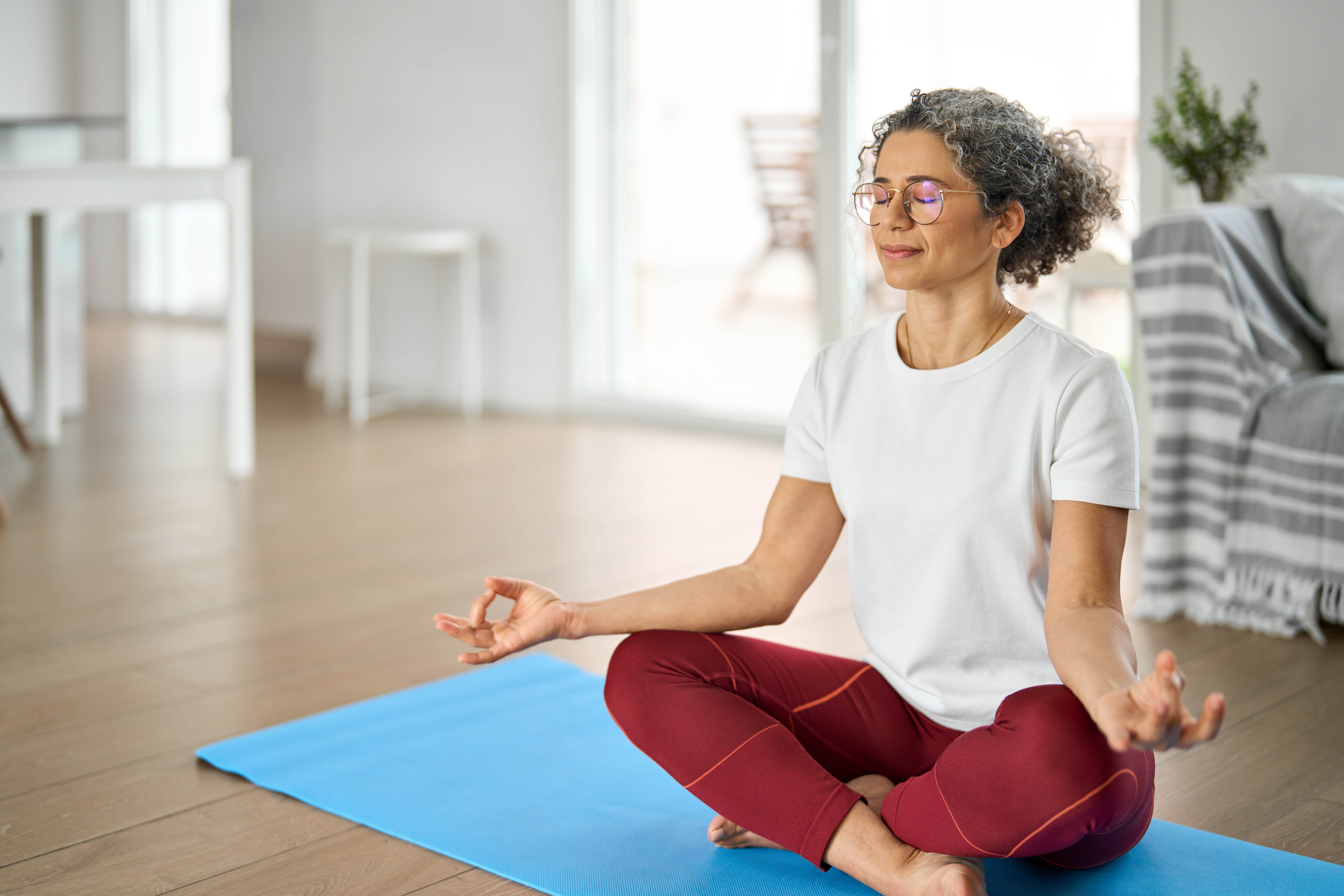 Middle aged woman doing yoga and meditating at home Middle aged woman doing yoga and meditating at home